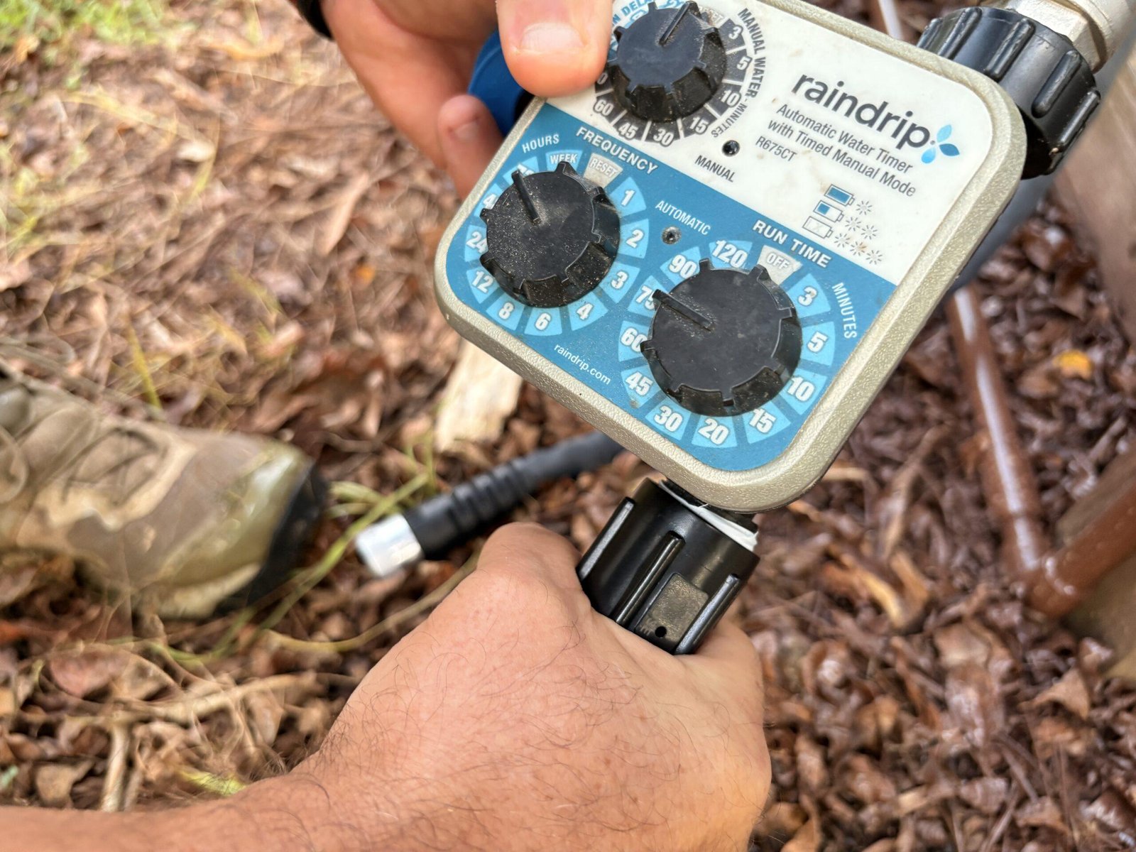 Close-up of hands connecting a garden hose to the water timer during installation