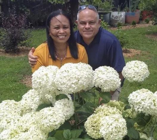 Bobby and Lynn of Bobby & Lynn’s Plant Farm standing behind white hydrangeas